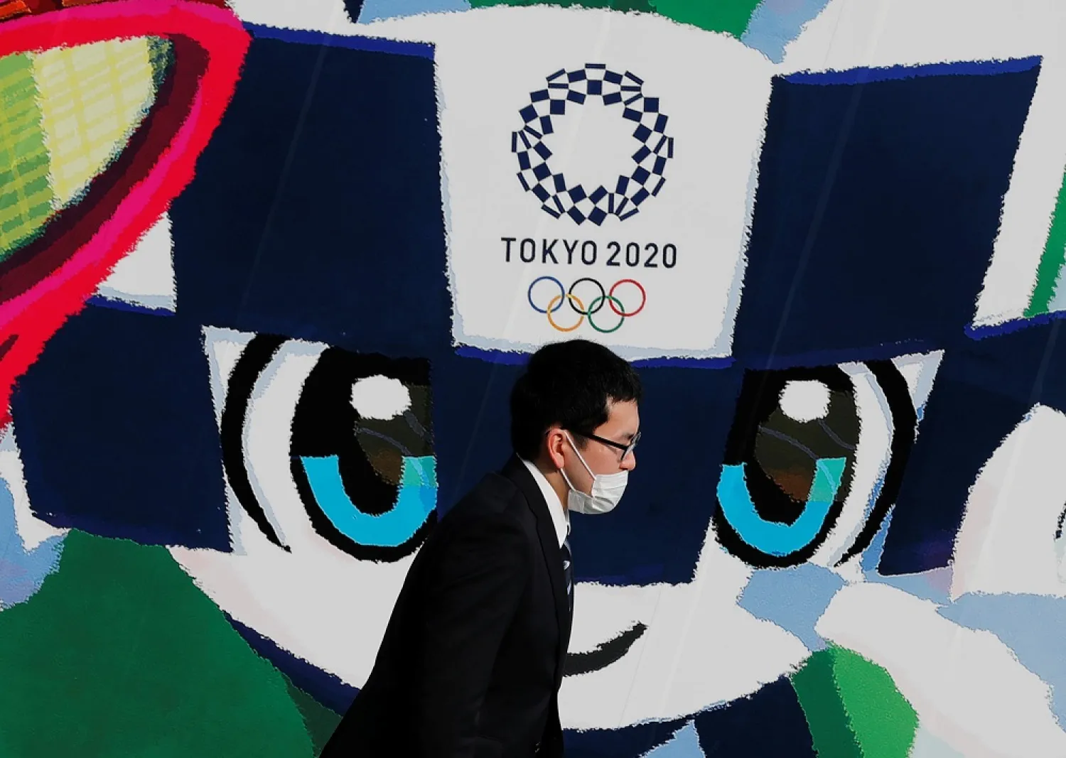A man wearing a protective mask walks past a large poster featuring Tokyo 2020 Olympic Games mascot Miraitowa amid the coronavirus outbreak in Tokyo, Japan June 4, 2020. (Reuters)