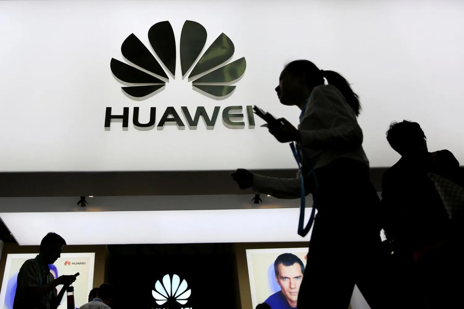 FILE PHOTO: People walk past a sign board of Huawei at CES (Consumer Electronics Show) Asia 2016 in Shanghai, China May 12, 2016. REUTERS/Aly Song