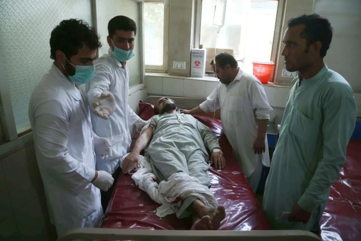 مسعفون يساعدون رجلاً أصيب في انفجار السيارة المفخخة (إ.ب.أ)