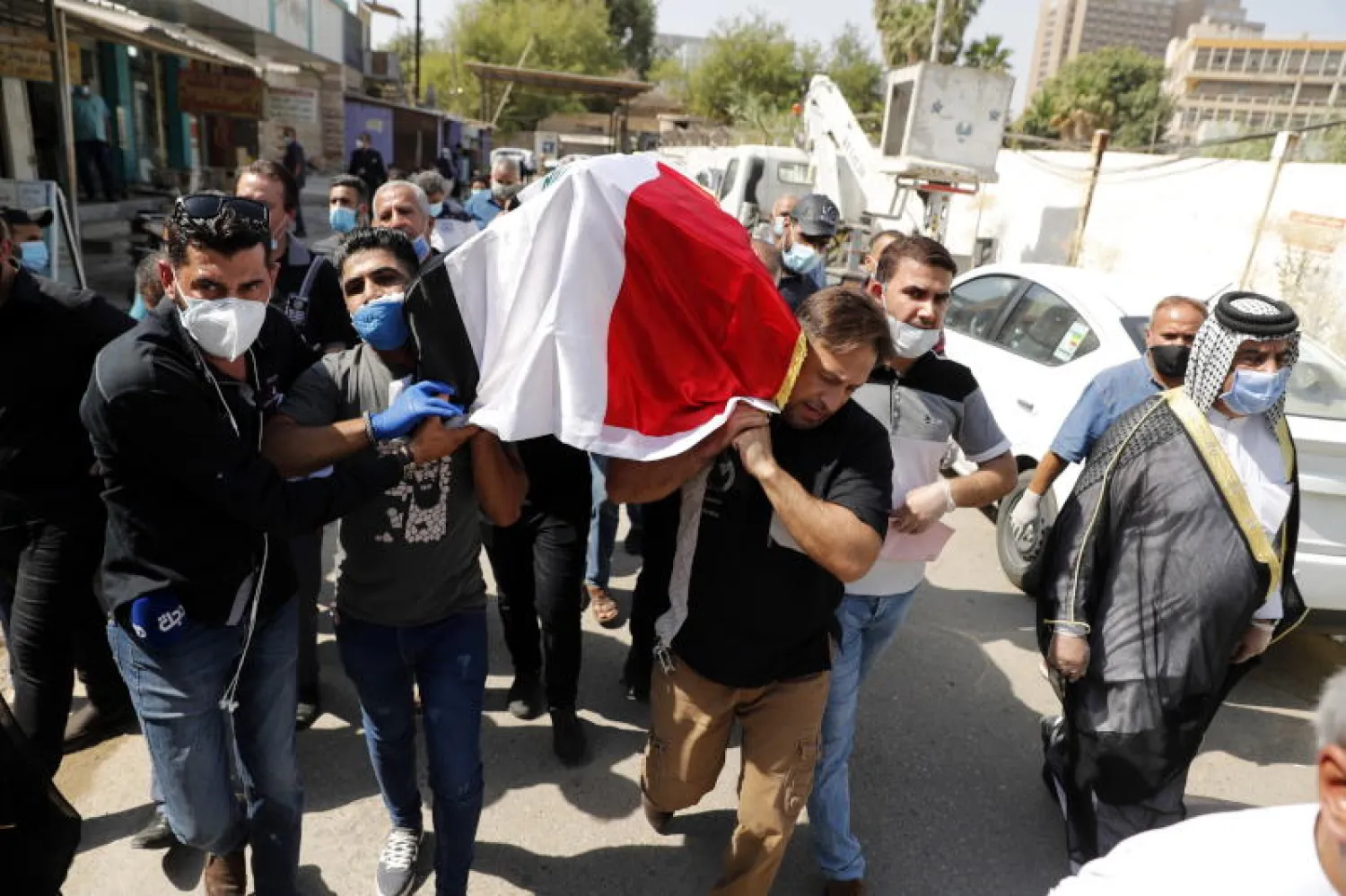 عراقيون يحملون نعش العراقي هشام الهاشمي الذي اغتيل على يد مجموعة مسلحة مجهولة خارج منزله (أ.ب.أ)