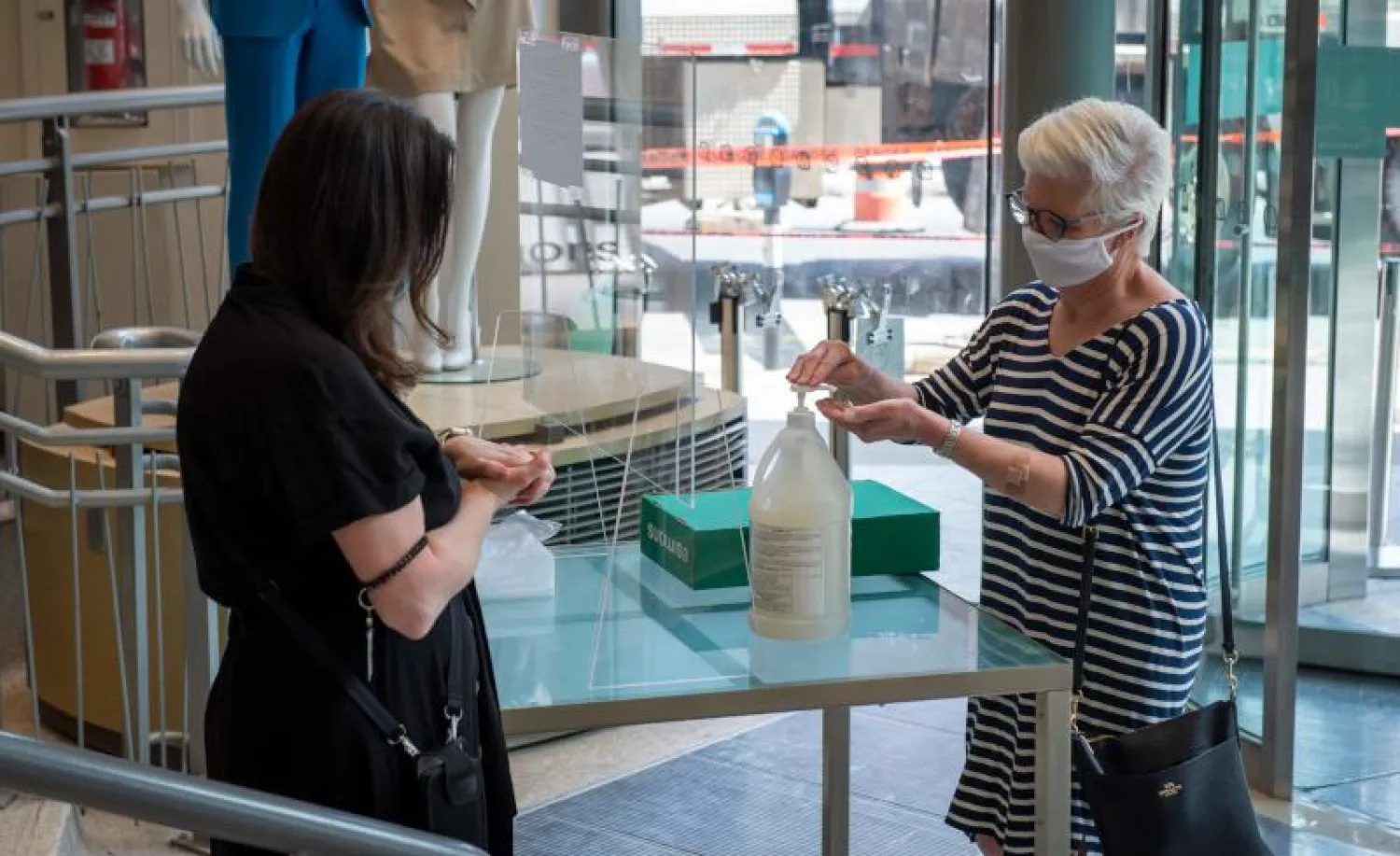 سيدة تعقّم يديها قبل دخولها متجراً في مونتريال (أ.ف.ب)