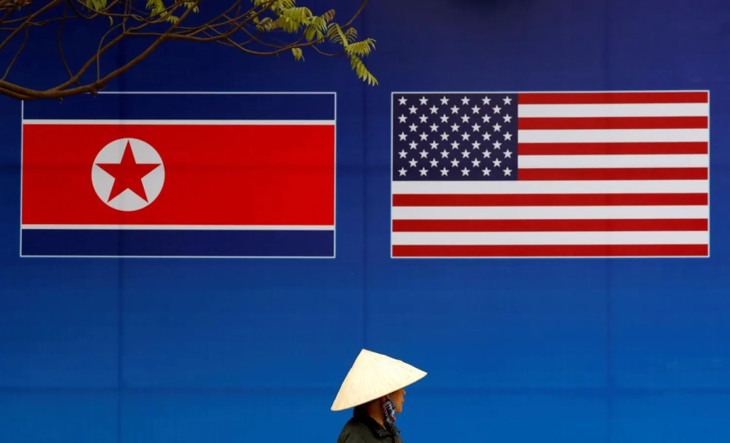 A person walks past a banner showing North Korean and US flags ahead of the North Korea-US summit in Hanoi, Vietnam, February 25, 2019. (Reuters)