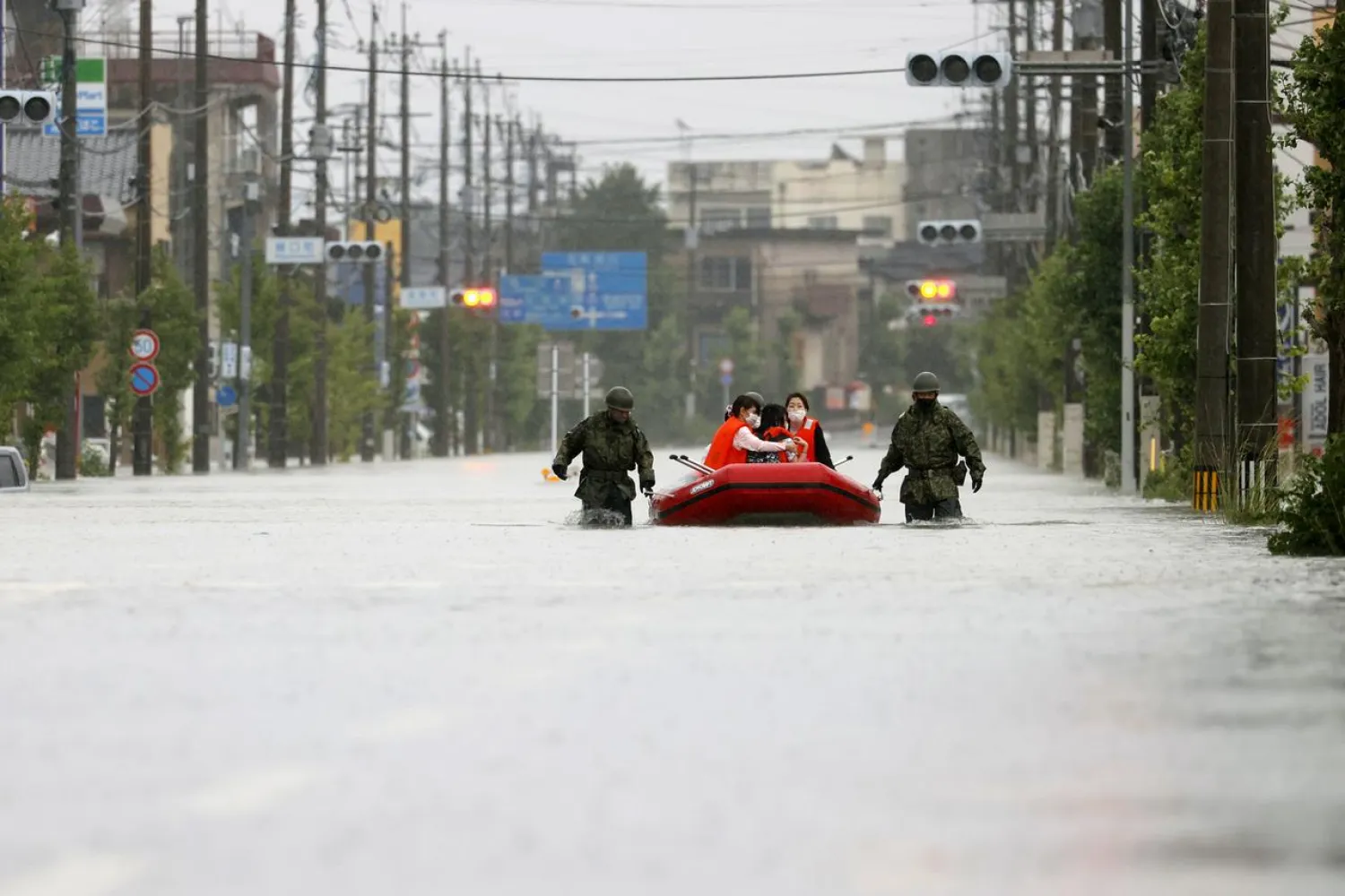 Residents are rescued by Japan Self-Defense Force soldiers using a rubber boat on a flooded road, caused by heavy rain in Omuta, Fukuoka prefecture, Japan July 7, 2020. (Kyodo via Reuters)
