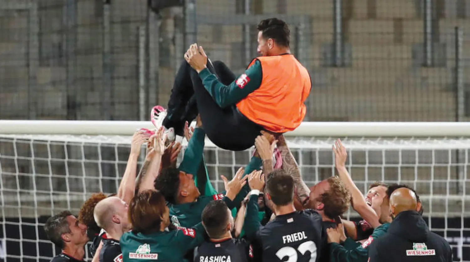 لاعبو بريمن يرفعون قائدهم بيزارو احتفالاً بالبقاء (أ.ب)