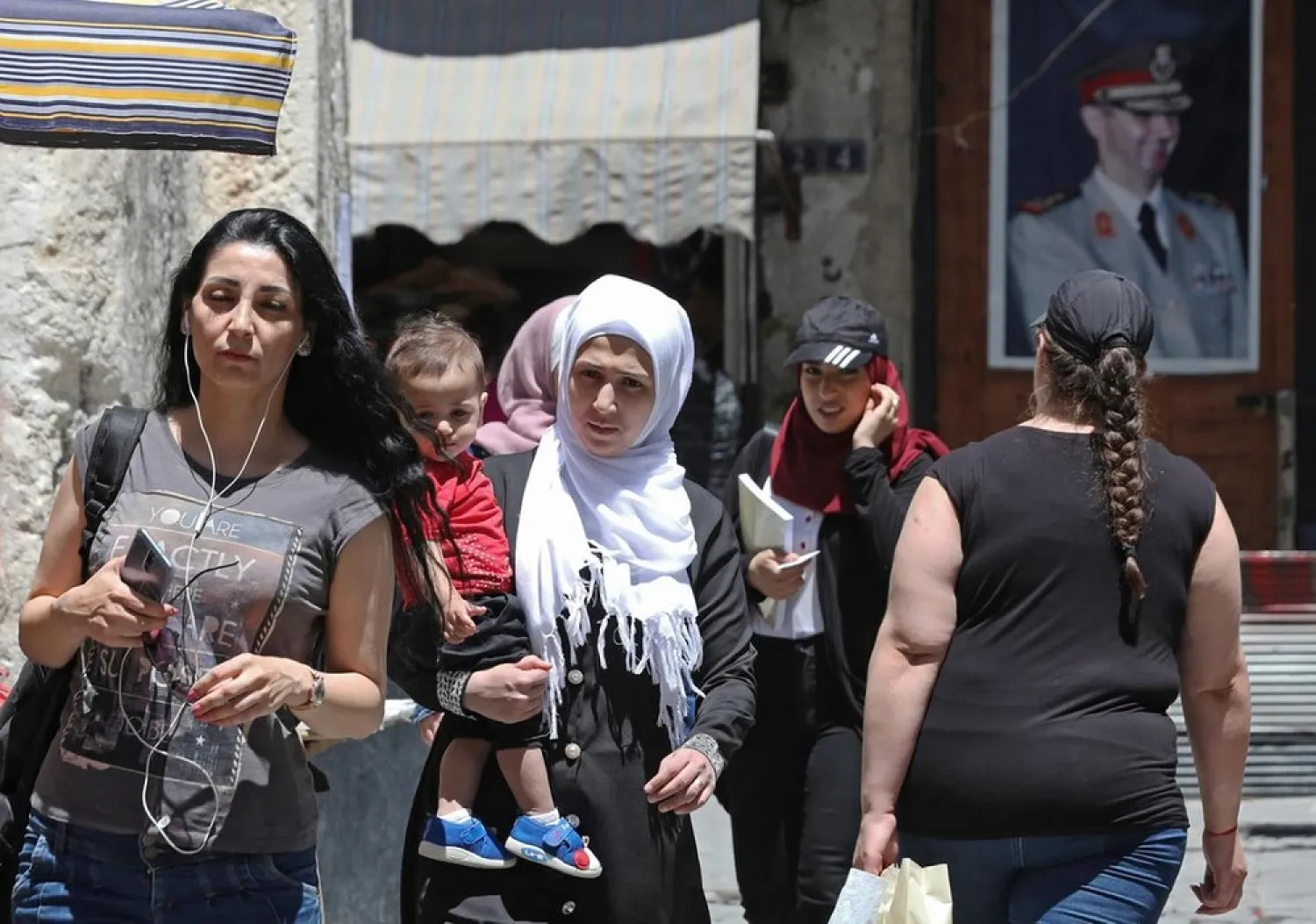 Syrians walk in old Damascus in front of a portrait of Syrian president Bashar Assad. (AFP)