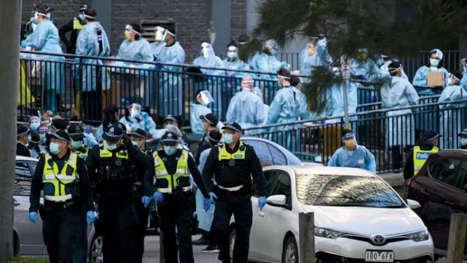 شرطيون وعمال صحة اجتمعوا خارج منطقة سكنية شهدت ارتفاعاً في الإصابات بملبورن أمس (إ.ب.أ)