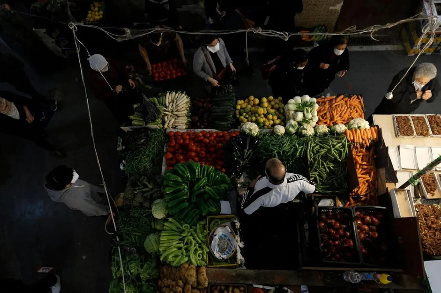 A vegetable vendor talks to a client at a food market in Algiers, Algeria, Tuesday April 21, 2020. (AP)