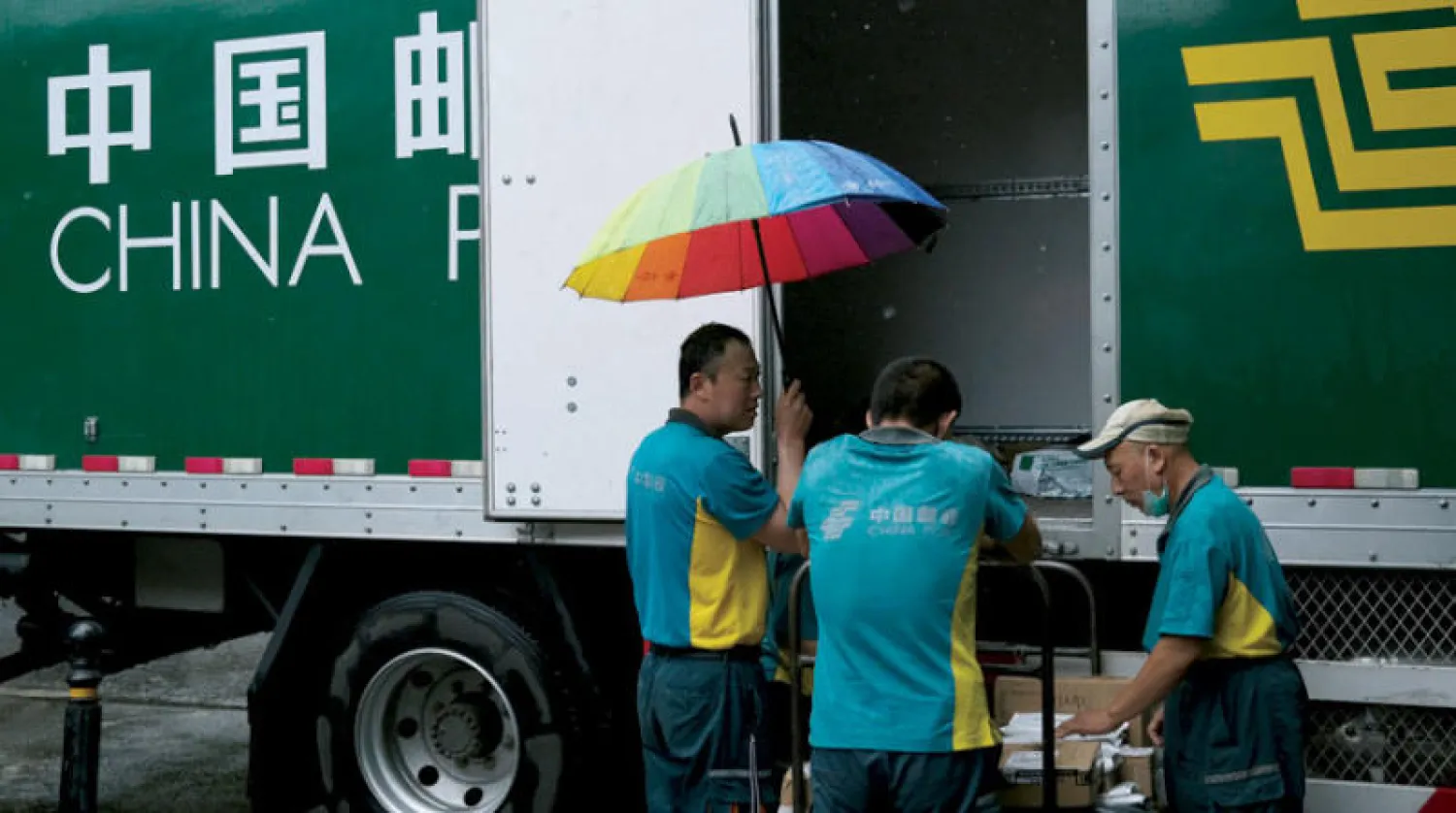 عمال توصيل طرود أثناء عملهم في بكين (رويترز)