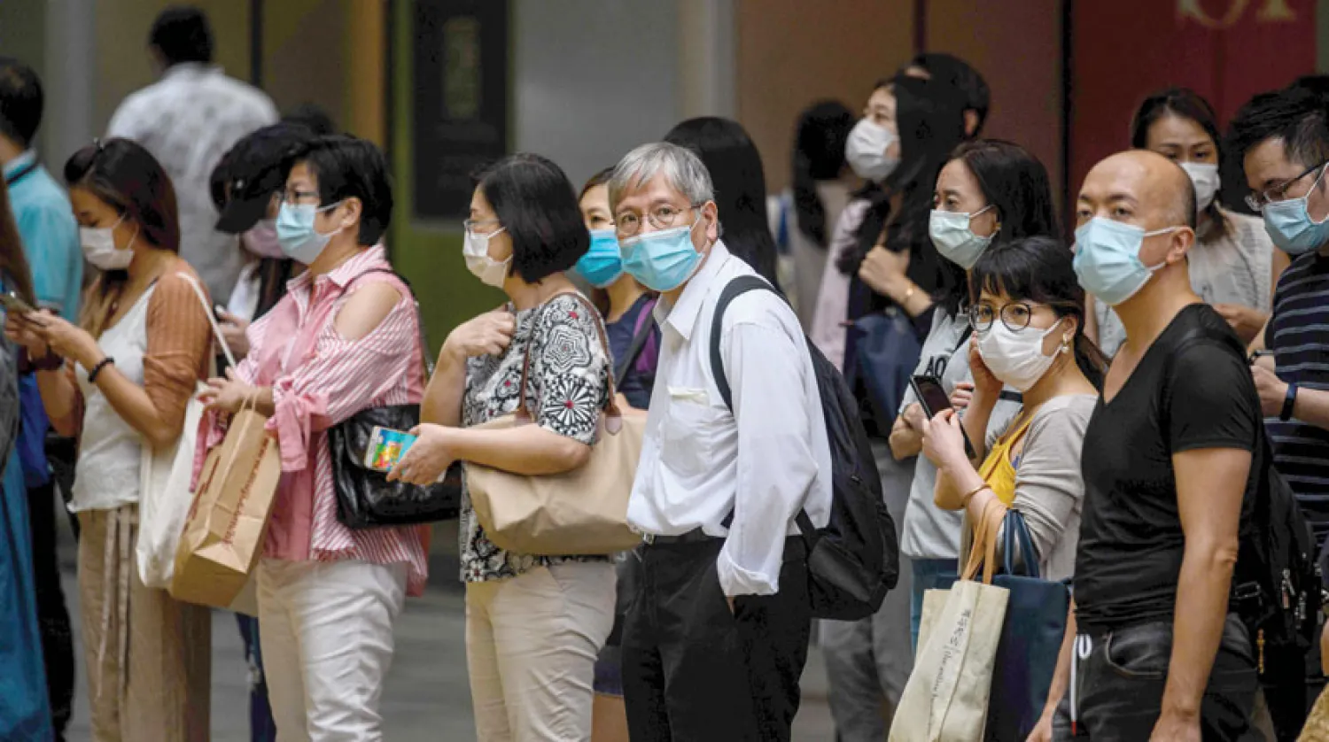 مشاة يرتدون كمامات في هونغ كونغ التي تشهد ارتفاعا جديدا في إصابات كورونا (أ.ف.ب)