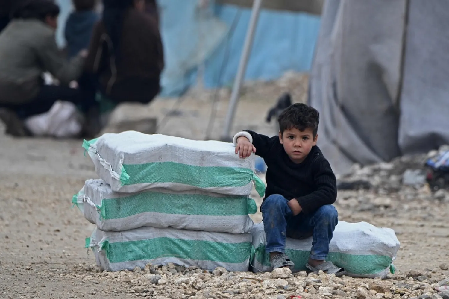A Syrian boy sits next to humanitarian aid, consisting of heating material and drinking water, at a camp along the border with Turkey. (AP)