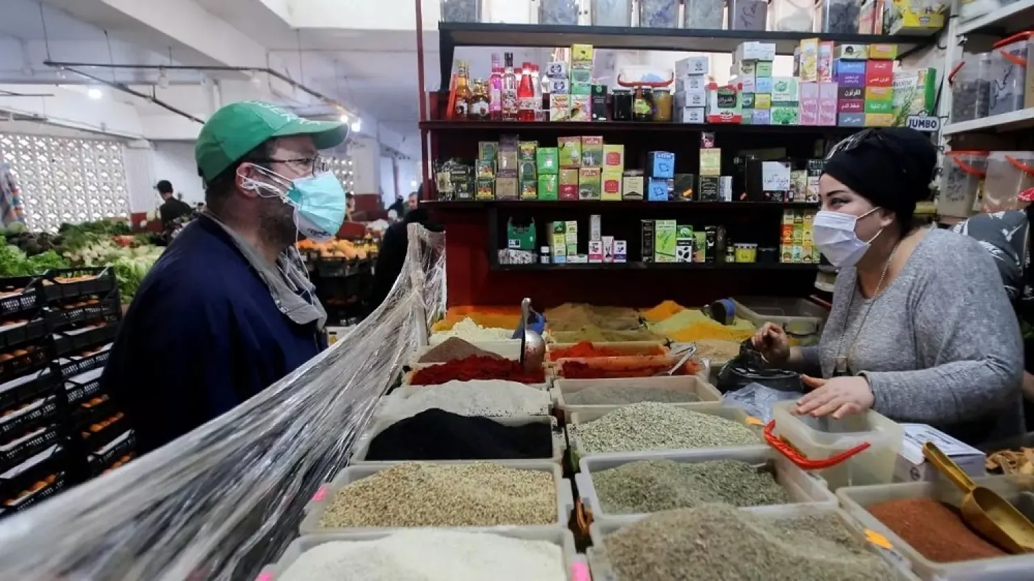 A vendor wearing a protective face mask serves a customer inside her shop, amid concerns over the coronavirus, in Algiers, Algeria April 19, 2020. (Reuters)