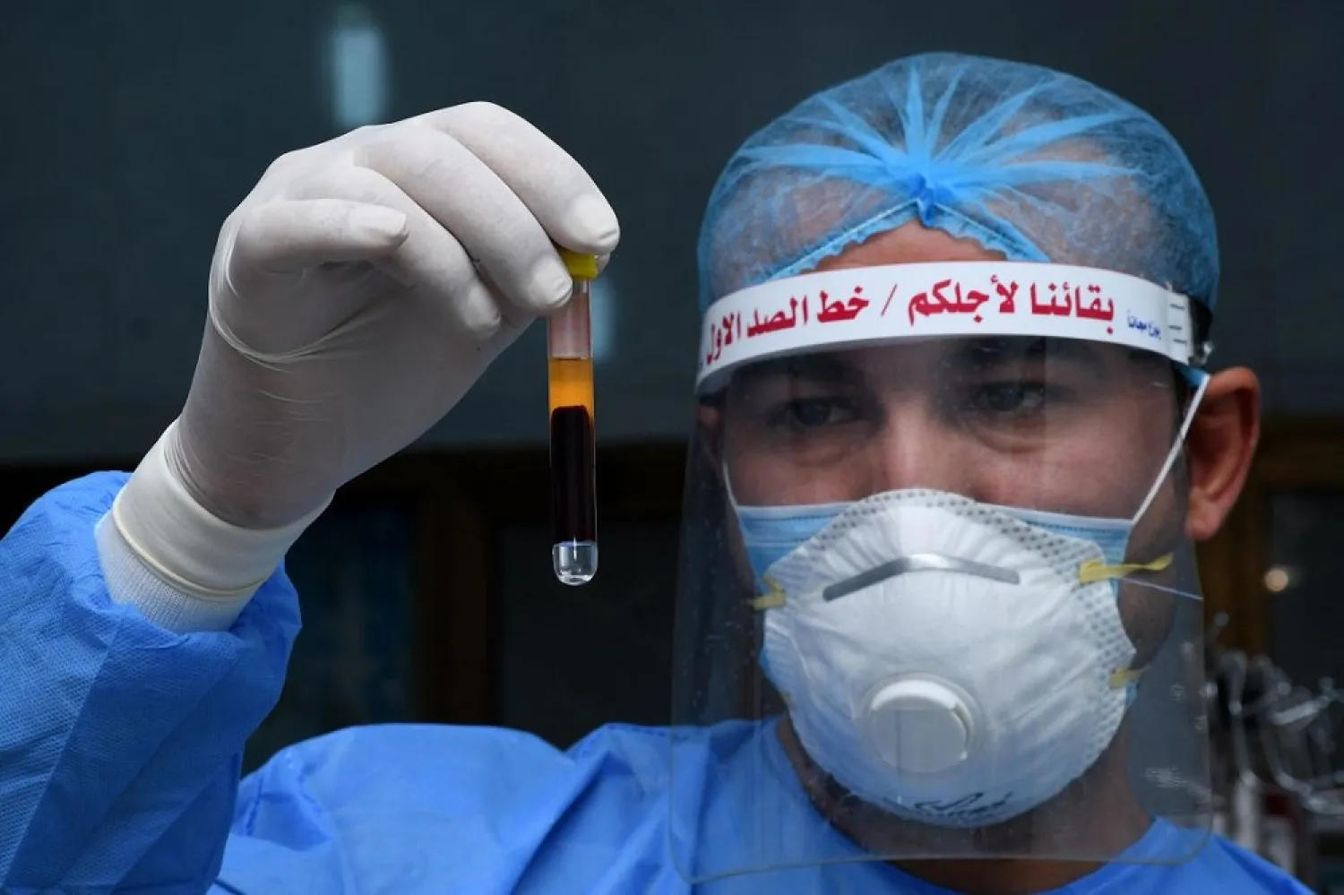 An Iraqi phlebotomist holds a test tube containing a blood sample of a recovered COVID-19 patient at the blood bank of Iraq's southern city of Nasiriyah, on June 24, 2020. (AFP)