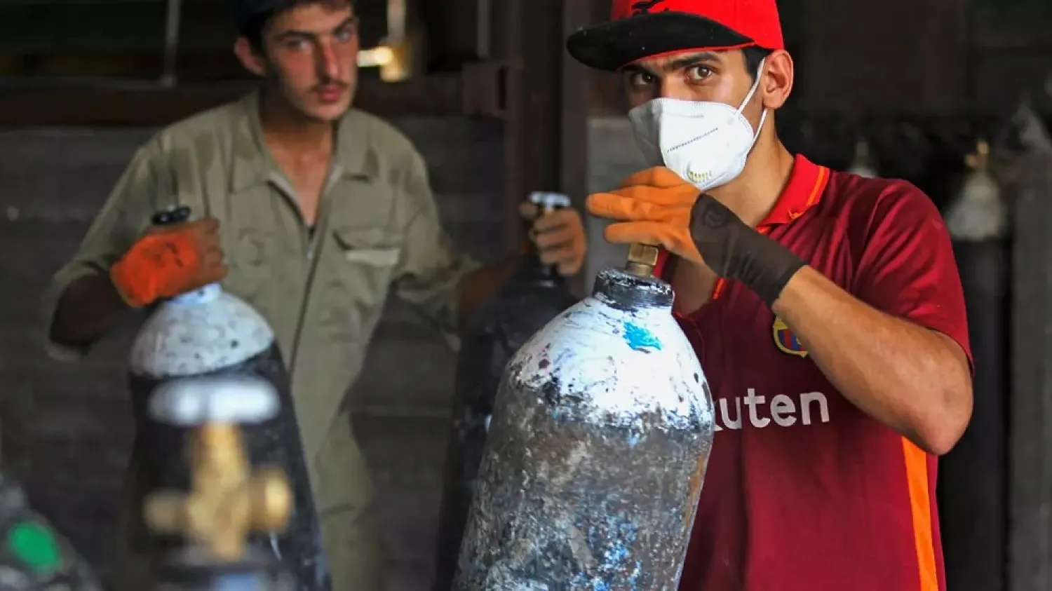 Mask-clad workers move refilled oxygen cylinders at a factory in Taji, north of Iraq's capital Baghdad, before delivering them to hospitals amid the COVID-19 pandemic. (AFP)