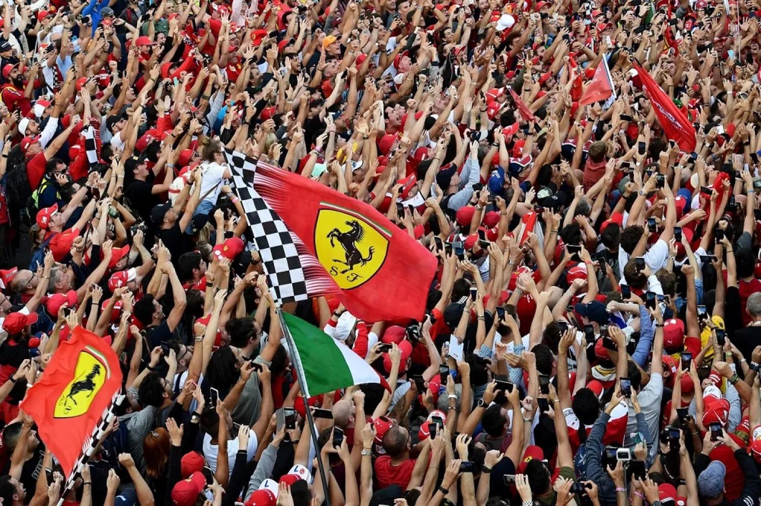 Scuderia Ferrari supporters, also known as 'Tifosi', and other fans cheer as they follow the awarding ceremony after the Italian F1 Grand Prix at Monza on September 8, 2019. (AFP)