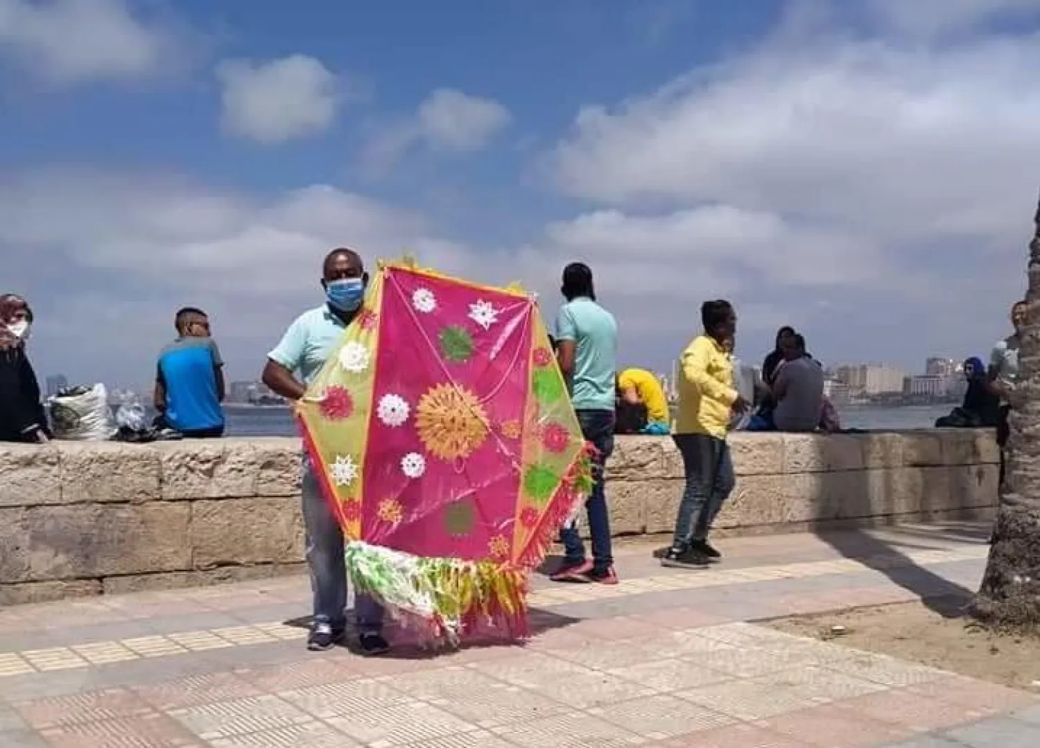 شخص يمسك بطائرة ورقية على الكورنيش (محافظة الإسكندرية - البوابة الإلكترونية)