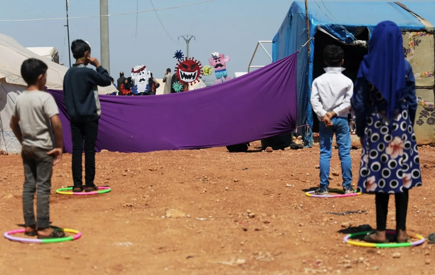 Displaced children attend a puppet show during an event aimed at spreading awareness amid COVID-19 fears, at a camp in the town of Maarat Masrin in Idlib, Syria, on April 14, 2020. (Reuters)