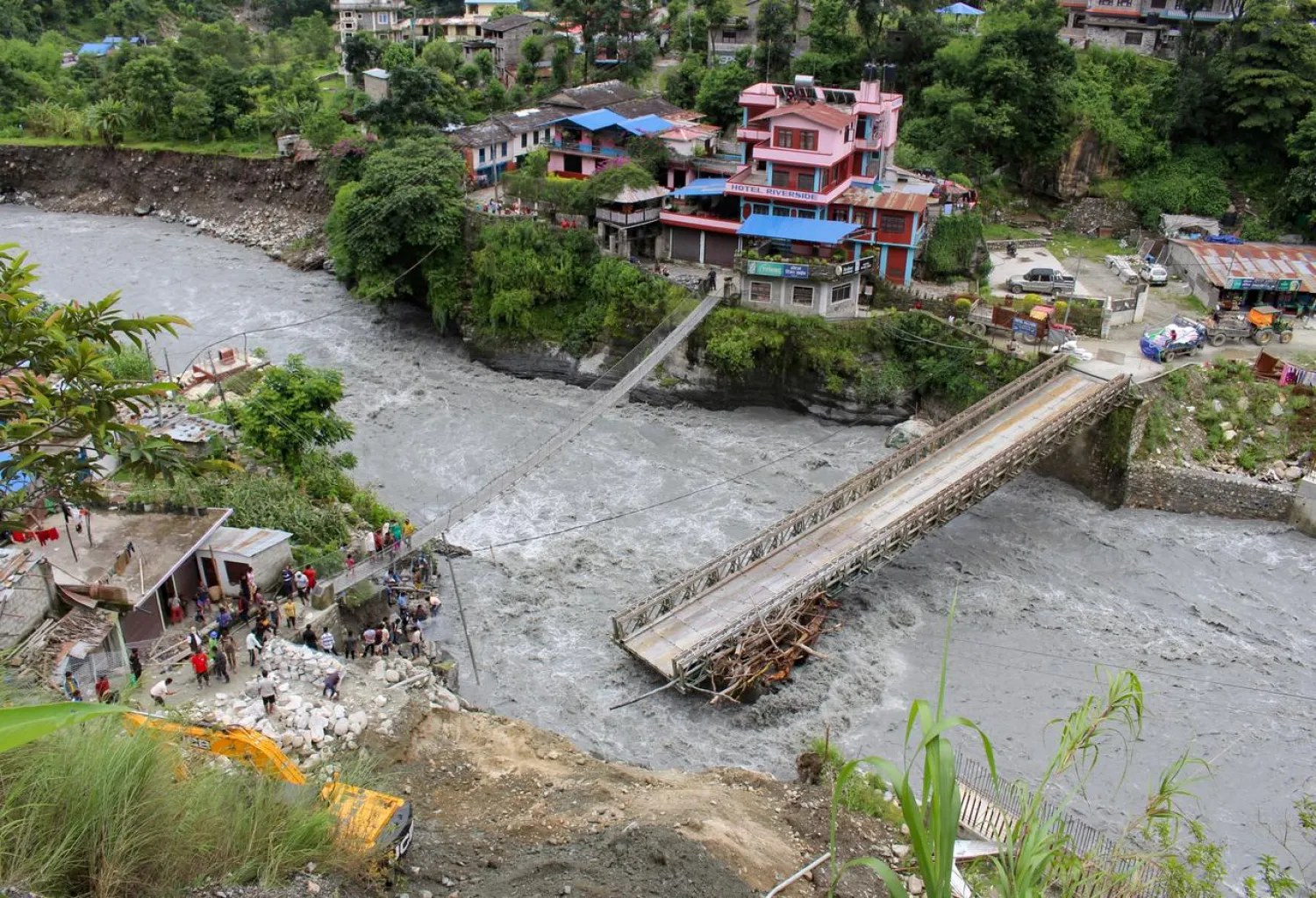 People gather near the bridge that is damaged due to the flood at Raghu Ganga River in Myagdi, Nepal July 11, 2020. (Reuters)