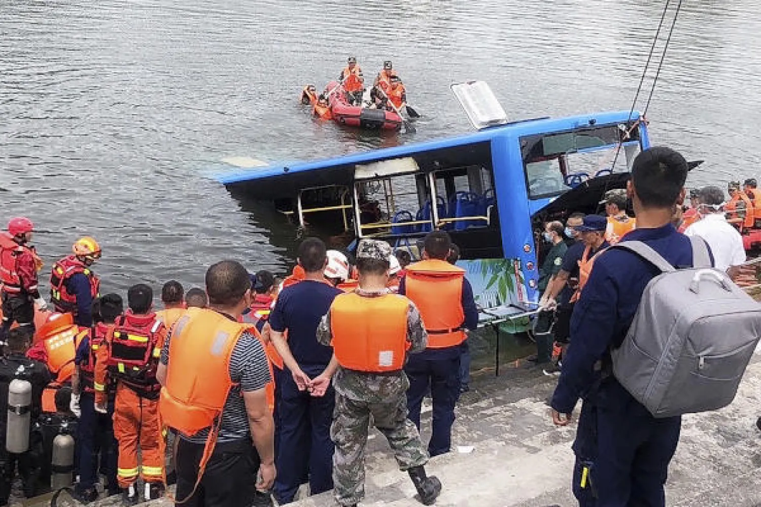 In this photo released by Xinhua News Agency, rescuers watch as a bus that fell into a lake is recovered in the Xixiu District of Anshun, southwestern China's Guizhou Province, Tuesday, July 7, 2020. Authorities say dozens were killed Tuesday when a bus ran through a roadside fence and plunged into a lake in the southwestern Chinese city. (Long Rui/Xinhua via AP)
