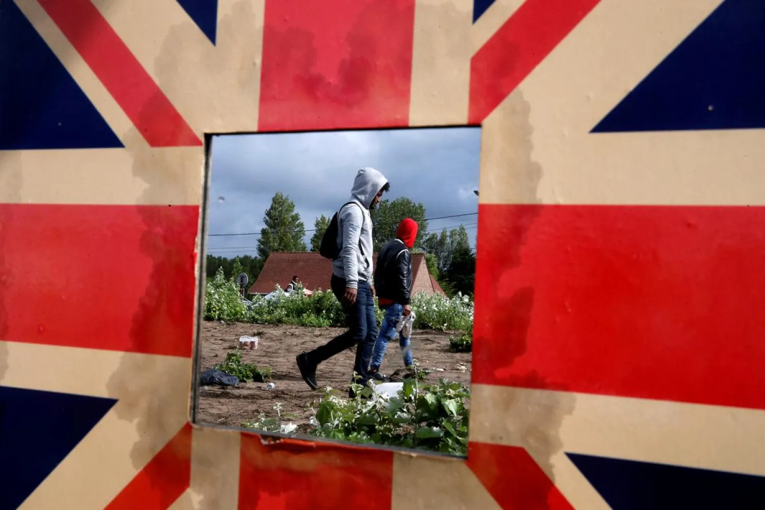 Migrants are reflected in a mirror bordered with the Union Jack as French police officers dismantle a makeshift shelter camp in Calais, France July 10, 2020. REUTERS/Pascal Rossignol
