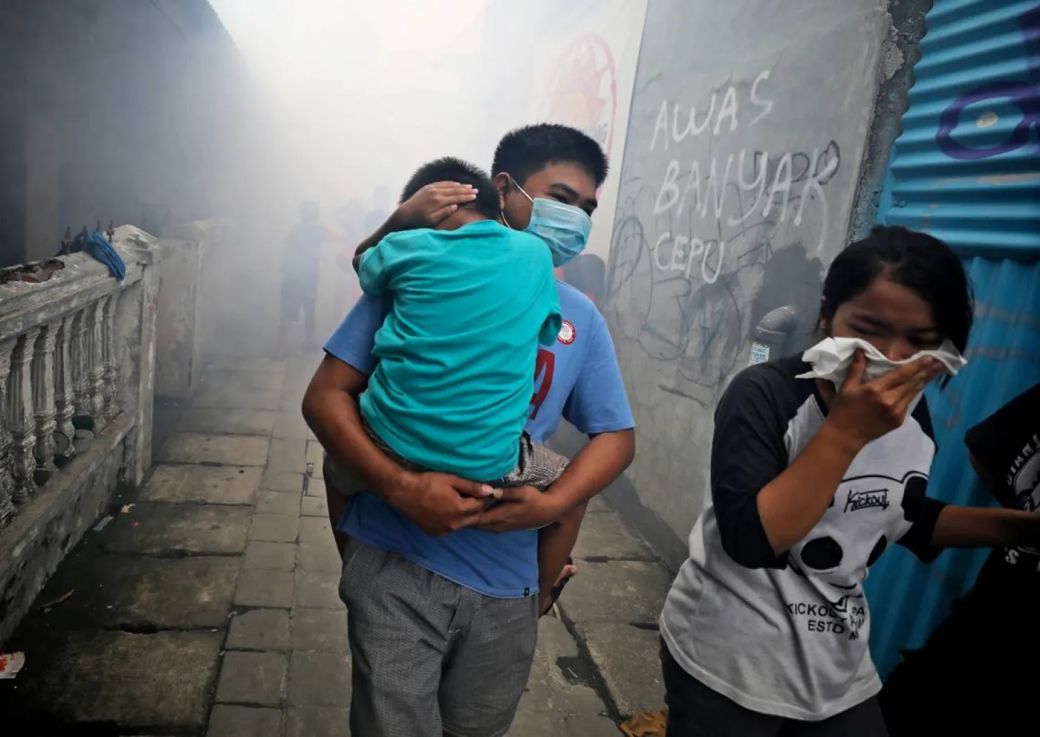 People move away as health workers fumigate a slum to prevent an outbreak of dengue fever in Jakarta, Indonesia, on Monday, March 23, 2020. (AP Photo/Dita Alangkara)