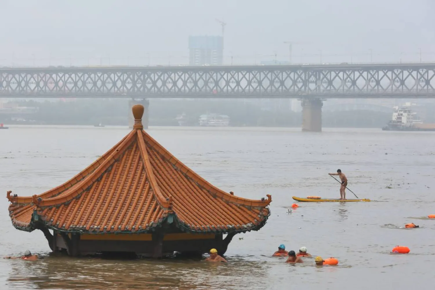 People swim near a pavilion partially submerged in floodwaters on the banks of the Yangtze River, following heavy rainfall in Wuhan, Hubei province, China July 8, 2020. (Reuters)