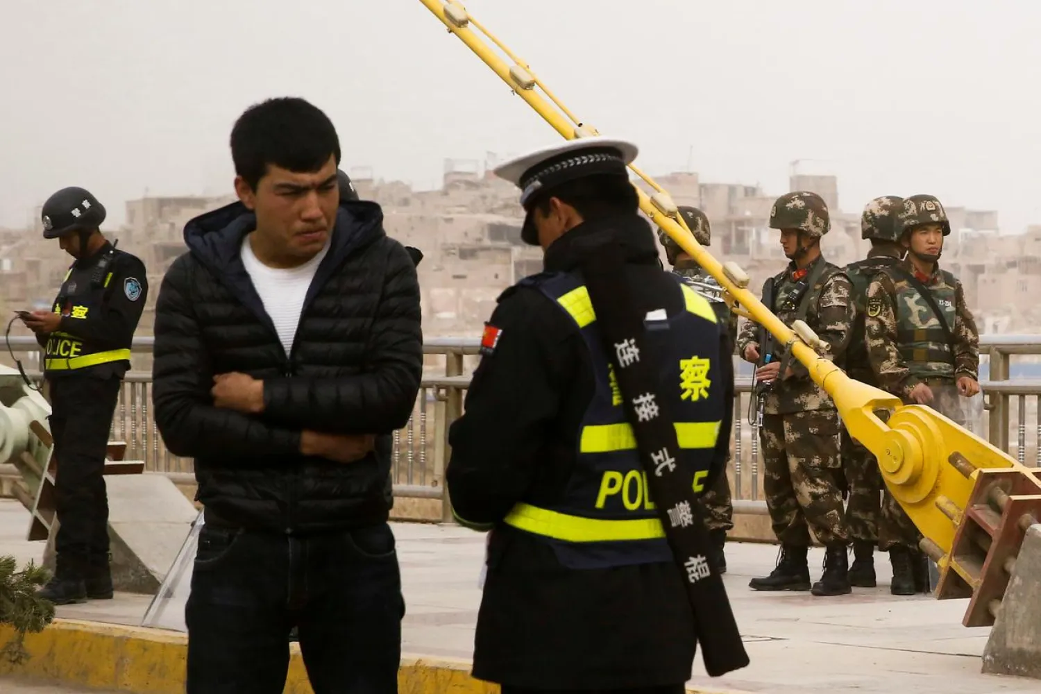 A police officer checks the identity card of a man as security forces keep watch in a street in Kashgar, Xinjiang Uighur Autonomous Region, China, March 24, 2017. REUTERS/Thomas Peter