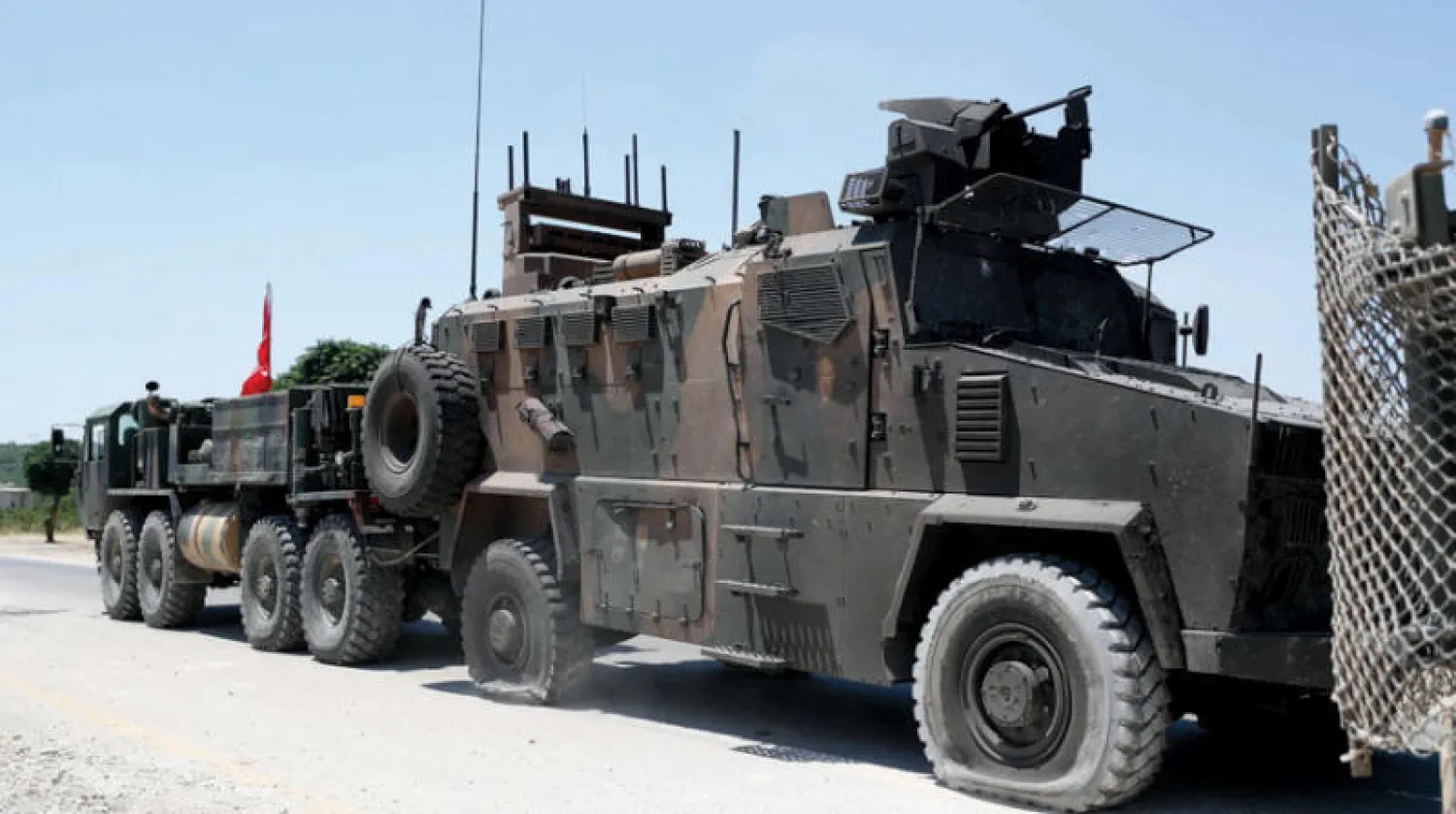 عربة تركية تسحب مدرعة تعرضت لأضرار بعد تفجير استهدفها على طريق حلب - اللاذقية أمس (أ.ف.ب)