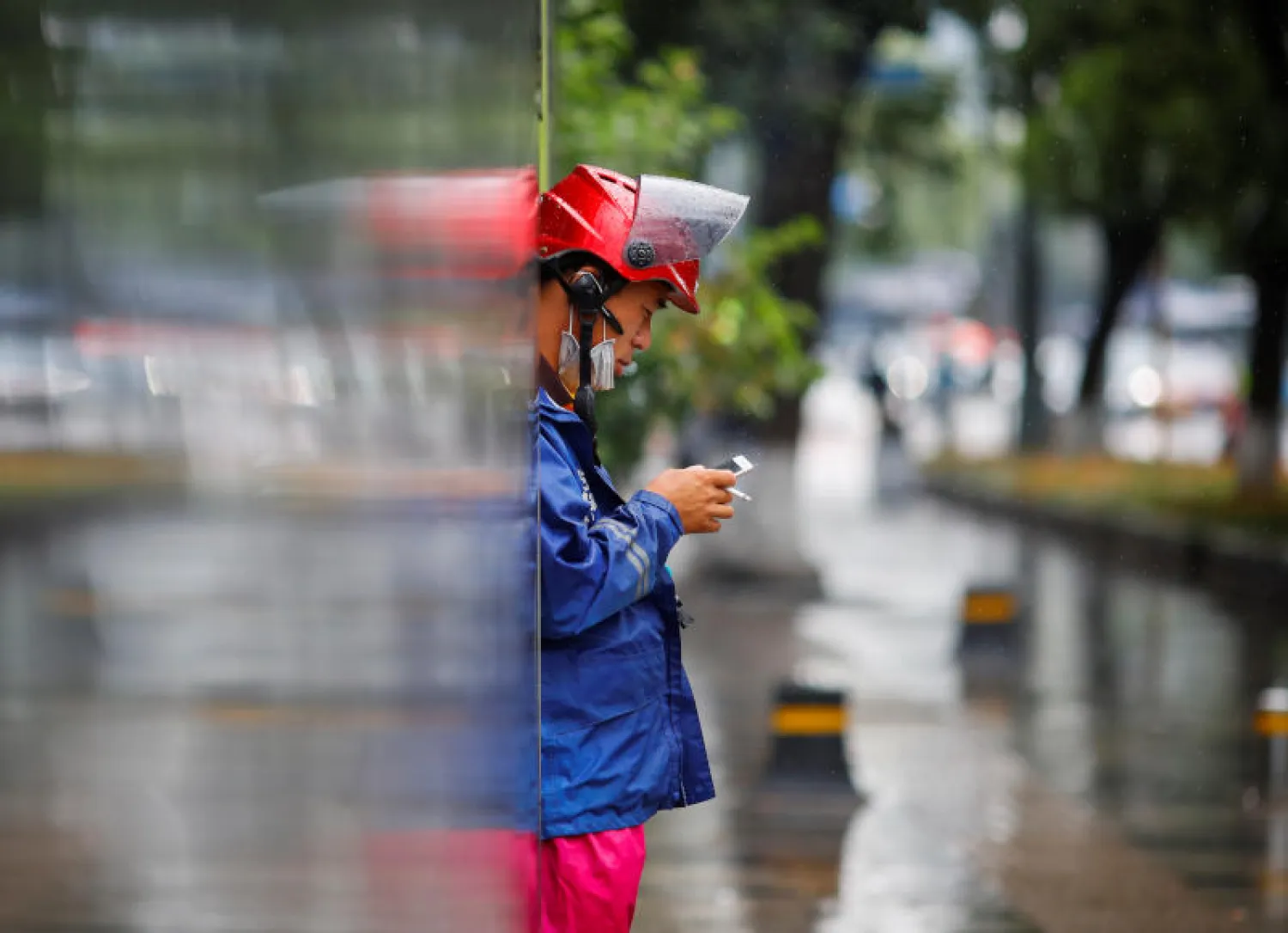 عامل توصيل يقوم بتدخين سيجارة أثناء ممارسته وظيفته في ظل انتشار كورونا بالصين (رويترز)