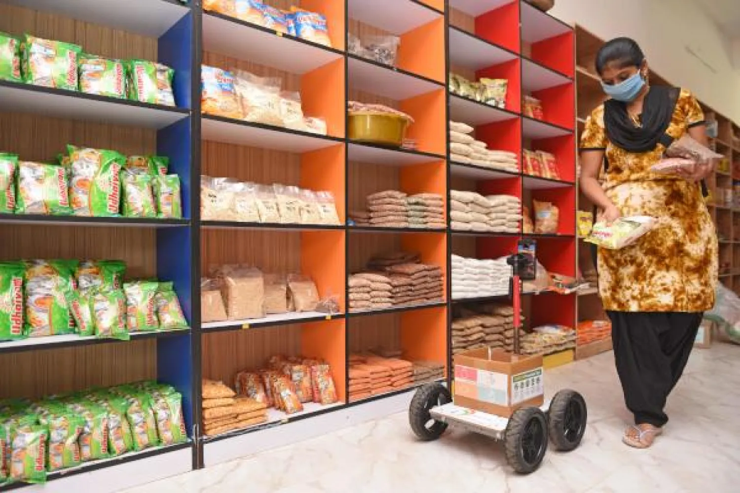 A store worker fills the tray of the robot with food items in Coimbatore, on May 13, 2020. - The robot has been self designed by an Indian engineer V. Karthi, from the southern district of Tamil Nadu, in order to maintain social distancing while shopping for basic commodities as a preventive measure against the COVID-19 coronavirus. (Photo by STR / AFP)
