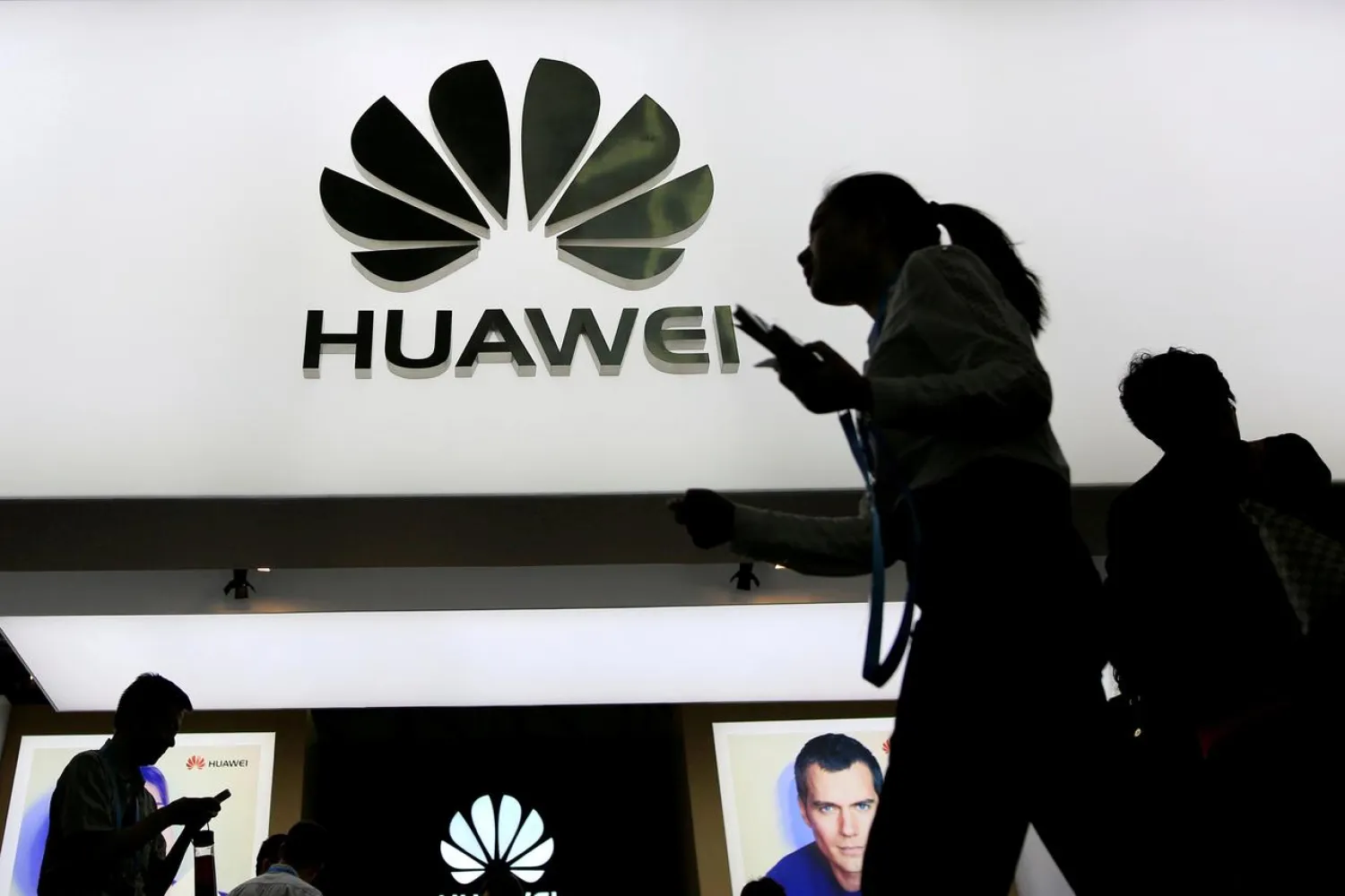 FILE PHOTO: People walk past a sign board of Huawei at CES (Consumer Electronics Show) Asia 2016 in Shanghai, China May 12, 2016. REUTERS/Aly Song/File Photo
