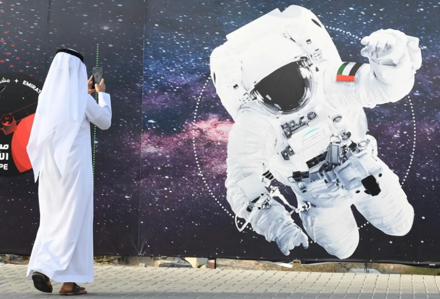 In this file photo from September 2019 a man takes a picture of an illustration of an astronaut with the Emirati national flag outside Dubai's Mohammed Bin Rashid Space Center. (AFP)