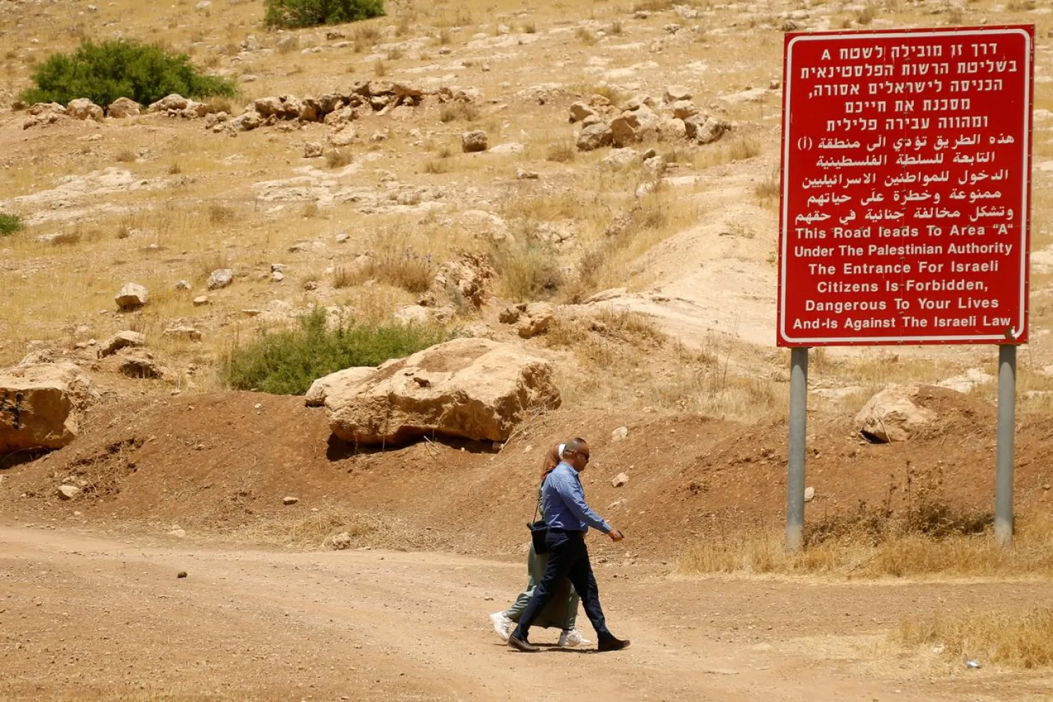 Palestinians walk past a sign with information on Area "A" in Jordan Valley in the Israeli-occupied West (File Photo: Reuters)