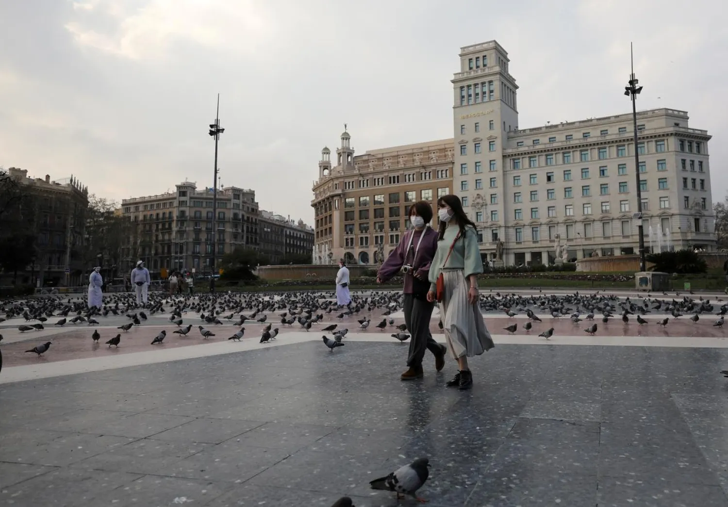 Women wear protective face masks as they walk through an empty Plaza de Catalunya (Catalonia Square), amidst concerns over coronavirus outbreak, in Barcelona, Spain March 14, 2020. (Reuters)