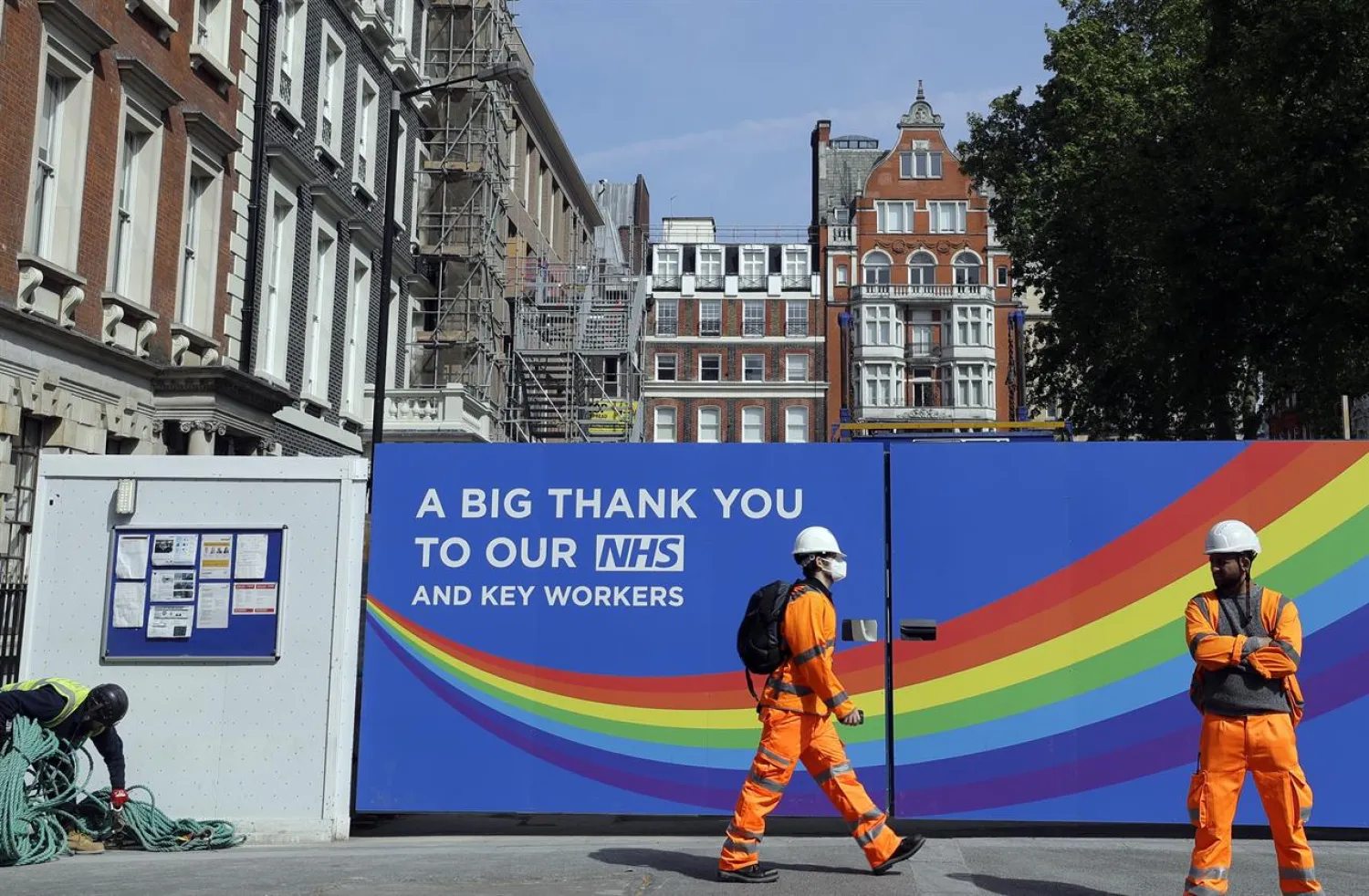 In this Thursday, May 7, 2020 file photo, a construction worker passes a sign thanking the NHS in London, as the country in is lockdown to prevent the spread of coronavirus. (AP Photo/Kirsty Wigglesworth, File)