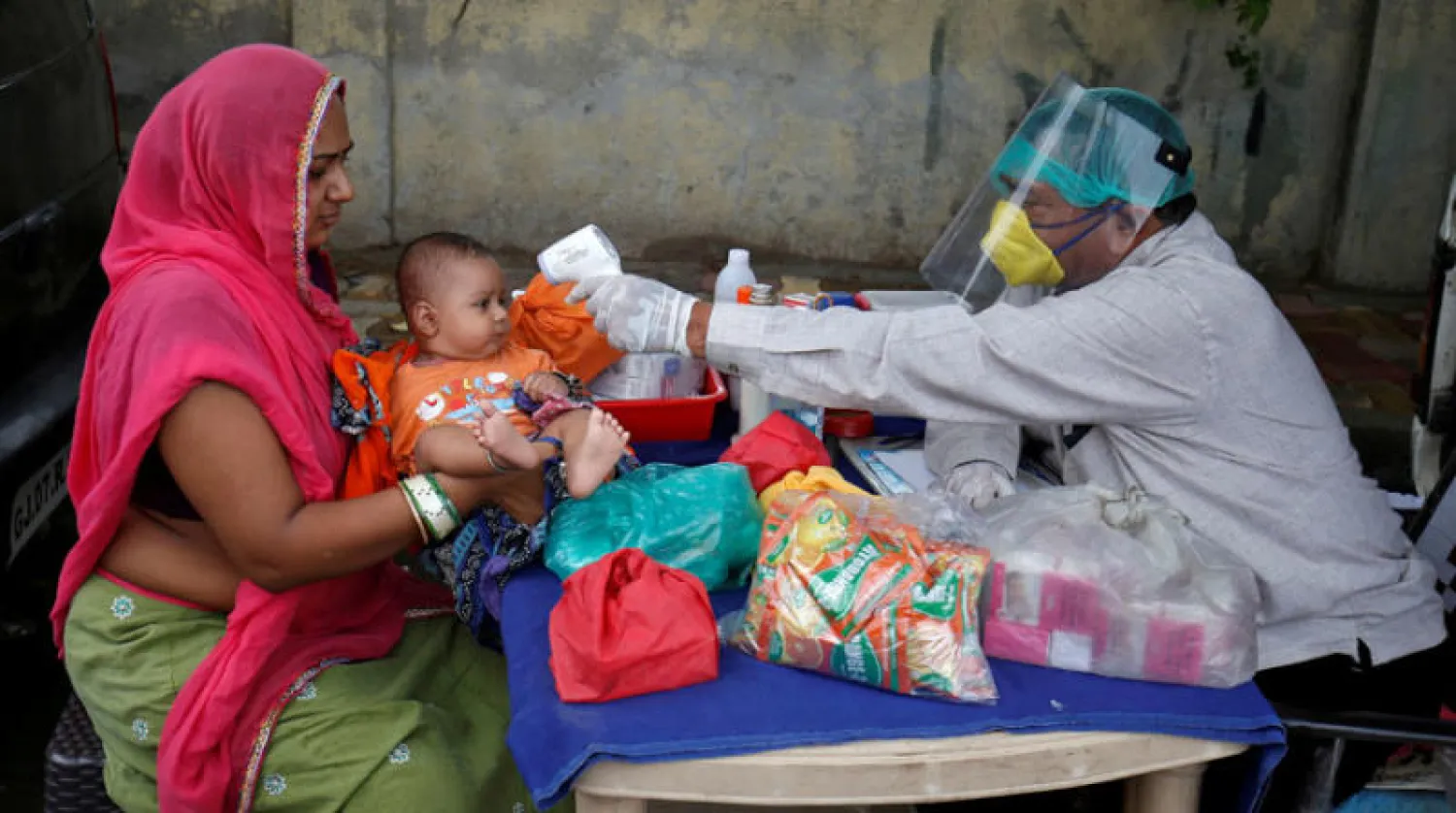 طبيب هندي يستخدم الأشعة تحت الحمراء لقياس درجة حرارة طفل (رويترز)