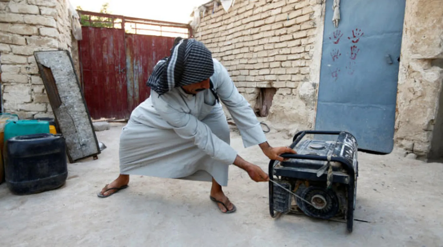 عراقي يحاول تشغيل مولد كهرباء في النجف وسط أزمة انقطاع التيار (رويترز)