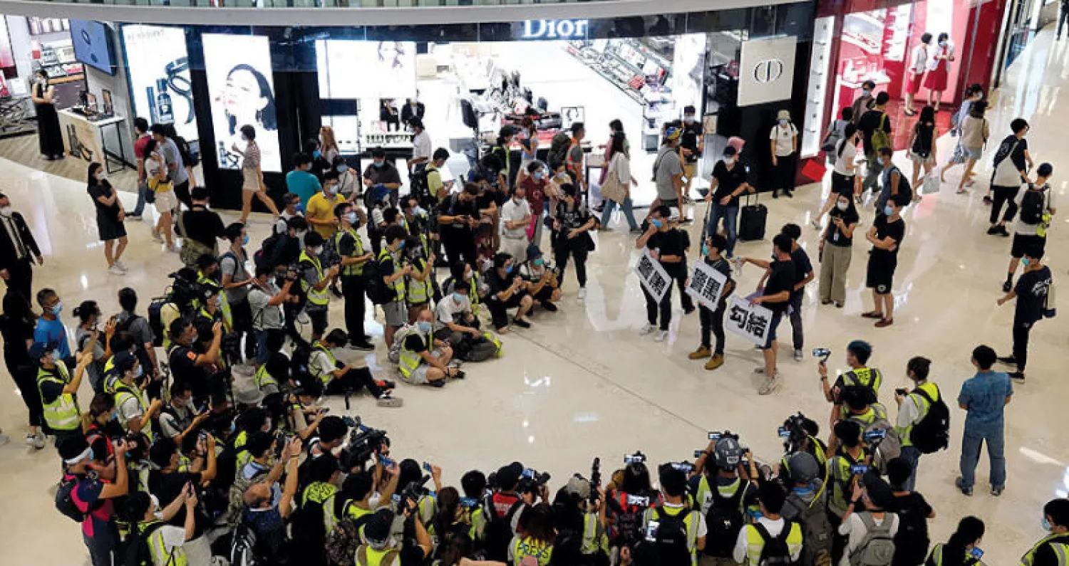 مسيرة لناشطين في هونغ كونغ أمس بمناسبة مرور عام على تعرض مؤيدين للديمقراطية لاعتداءات من ملثمين في منطقة يوين لونغ (رويترز)