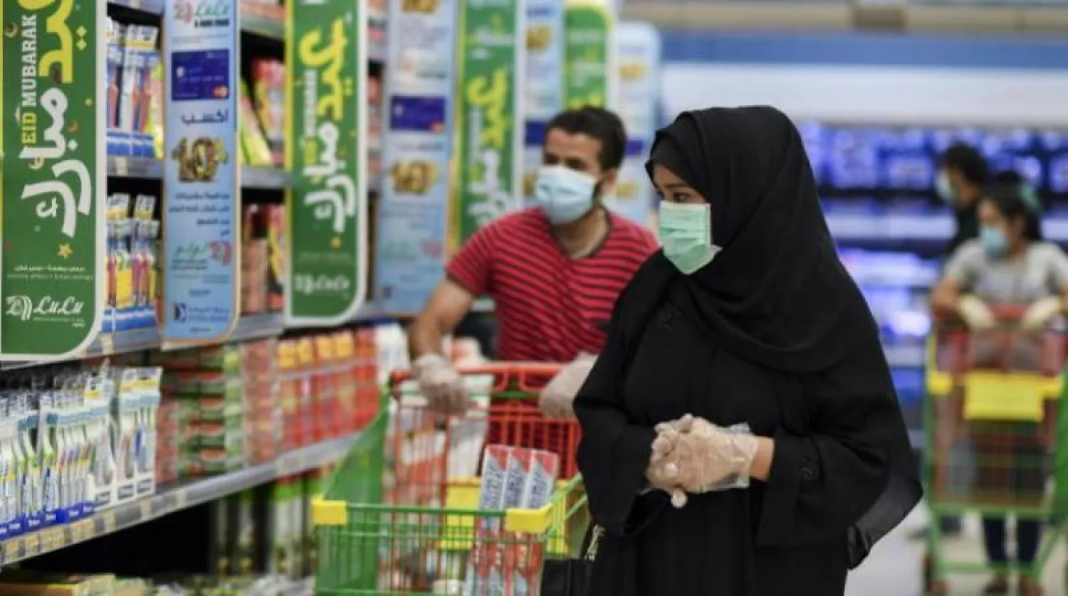 زوجان يضعان قناعين واقيين أثناء التسوق داخل «هايبر ماركت» في الدوحة (إ.ب.أ)