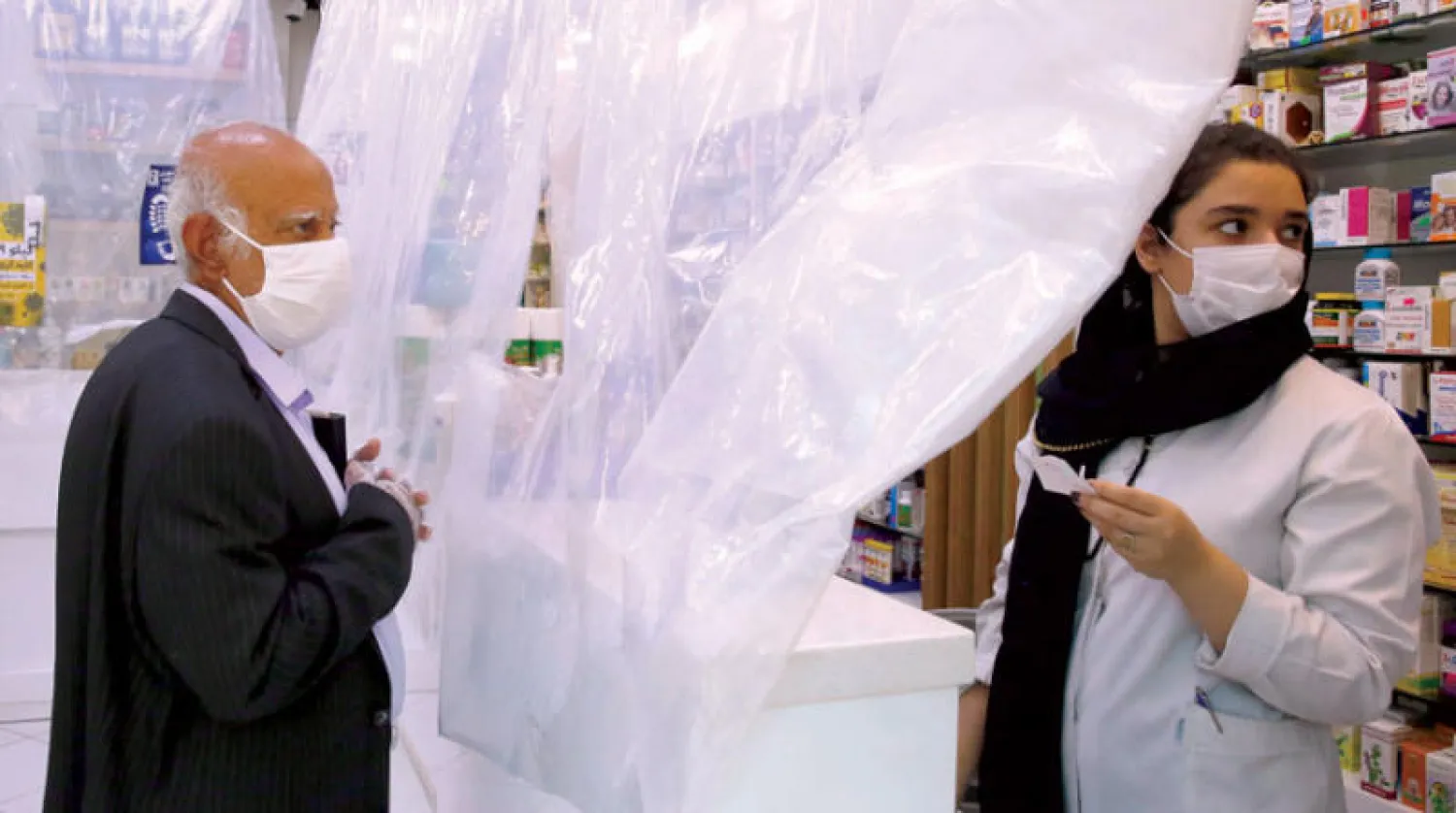 صيدلانية تتحدث إلى رجل في طهران التي تشكو من عقوبات واشنطن وسط أزمة وباء «كورونا» الحادة في إيران (إ.ب.أ)