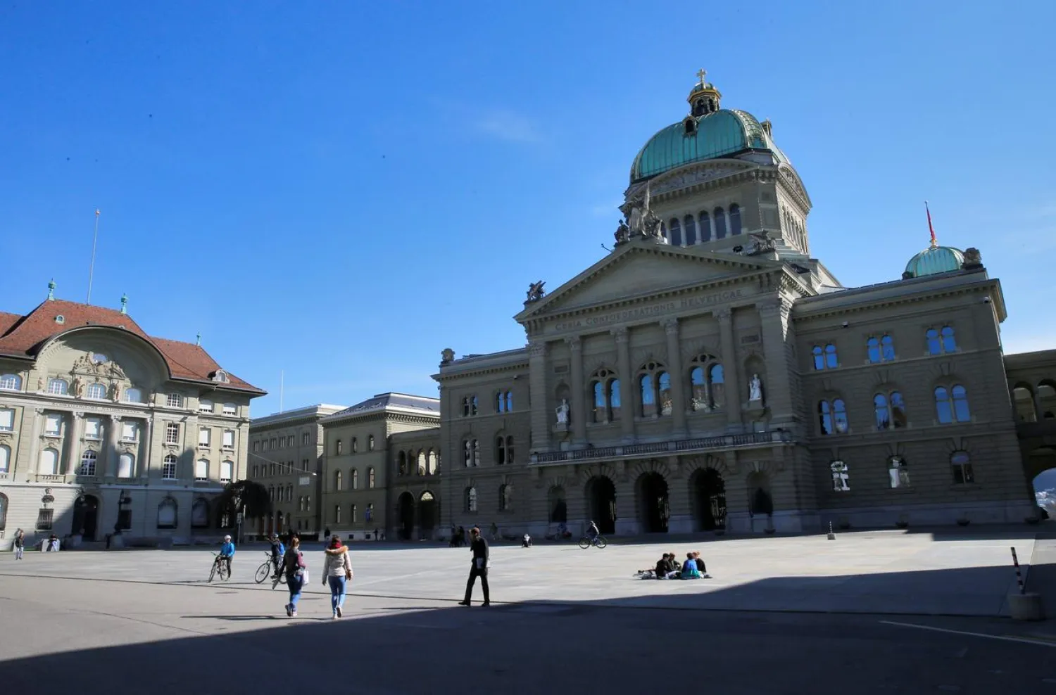 People sit on the empty square in front of the Swiss Parliament Building during a federal council meeting on the outbreak of the coronavirus in Bern, Switzerland, March 16, 2020. (Reuters)