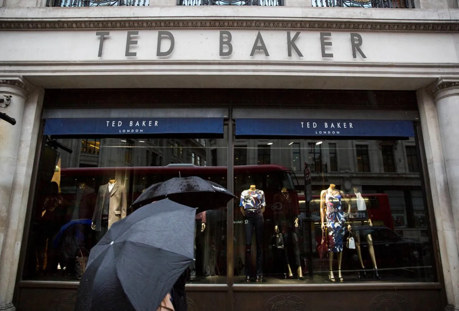 People shelter under umbrellas as they pass a Ted Baker a store in London, Britain October 6, 2015. (Reuters)