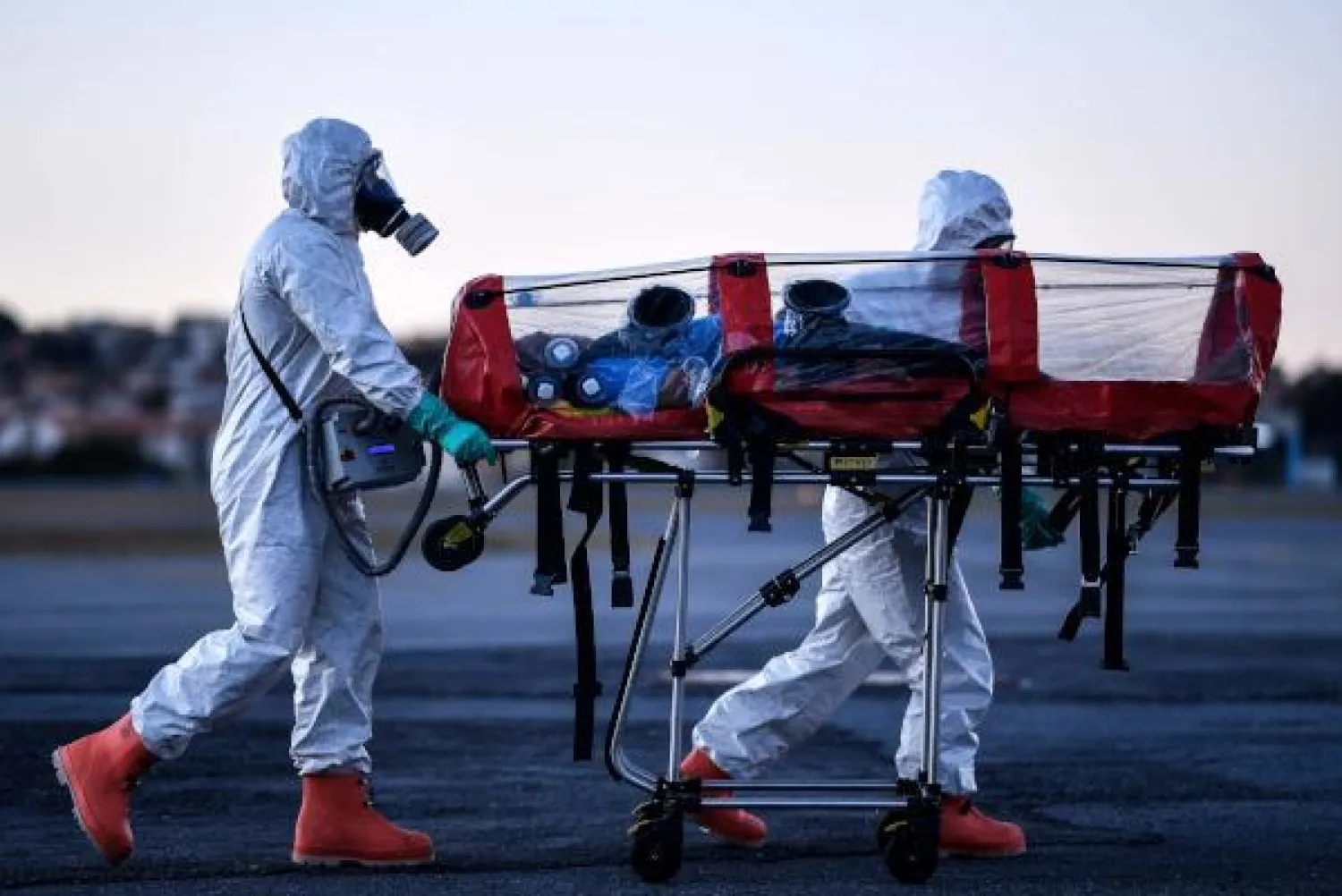 أعضاء فرقة عسكرية للدفاع المدني ينقلون مرضى كورونا في مطار بامبولها بالبرازيل (ا.ف.ب)