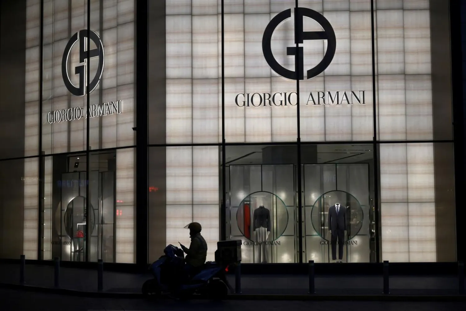 A deliveryman is seen silhouetted in front of a Giorgio Armani store at the Wangfujing shopping street, in Beijing, China February 20, 2020. (Reuters)
