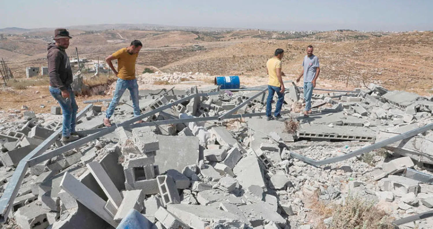 مواطنون يتفقدون ركام منزل هدمته إسرائيل الثلاثاء في بلدة بني نجم بالضفة (أ.ف.ب)