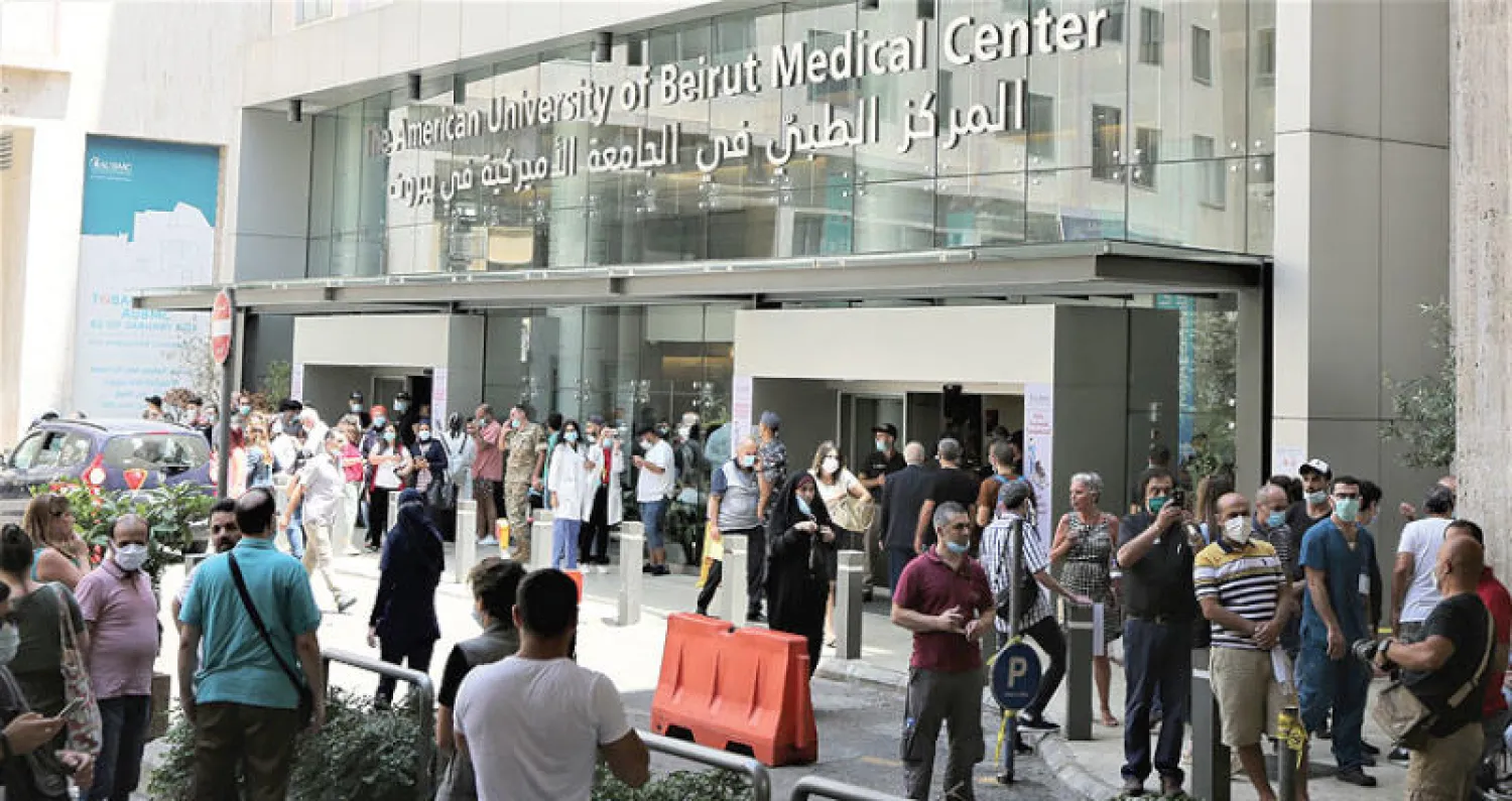 الموظفون المصروفون من العمل أمام مدخل المركز الطبي في الجامعة الأميركية (إ.ب.أ)