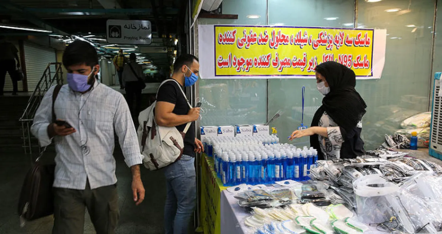 إيرانية تبيع كمامات ومواد تعقيم في مدخل محطة لمترو الأنفاق وسط العاصمة طهران أمس (أ.ف.ب)