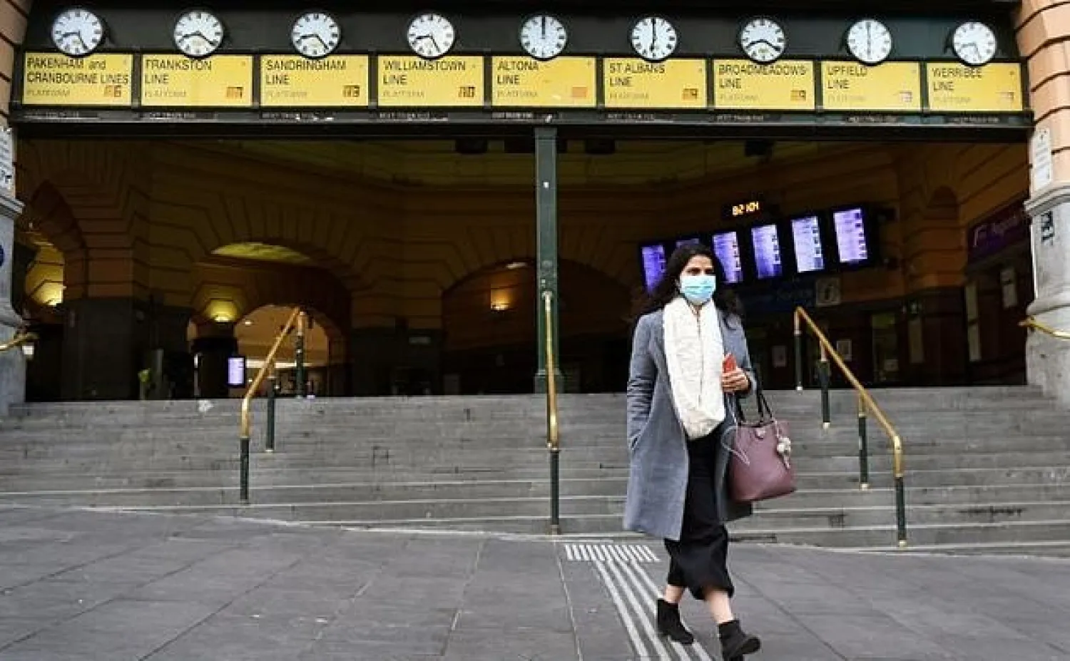 A commuter walks out of Melbourne's Flinders Street Station, wearing a mask. AFP