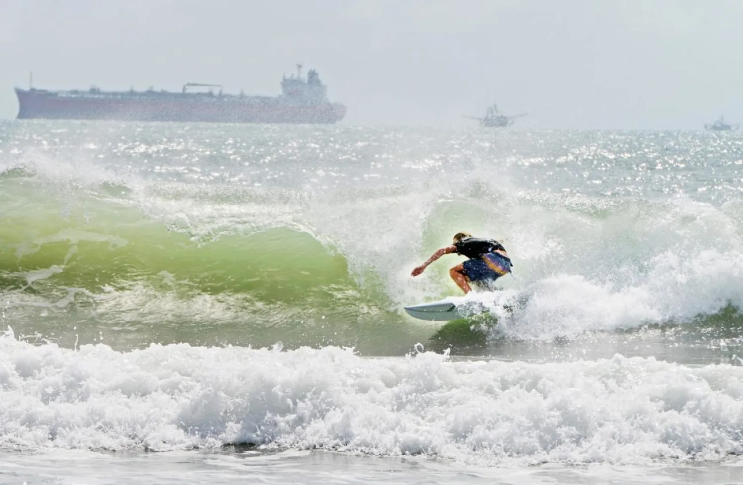A surfer catches a barrel ride Friday, July 24, 2020, as swell waves approach the coast of South Padre Island, Texas, due to Tropical Storm Hanna approaching the Texas Gulf Coast. (Miguel Roberts/The Brownsville Herald via AP)