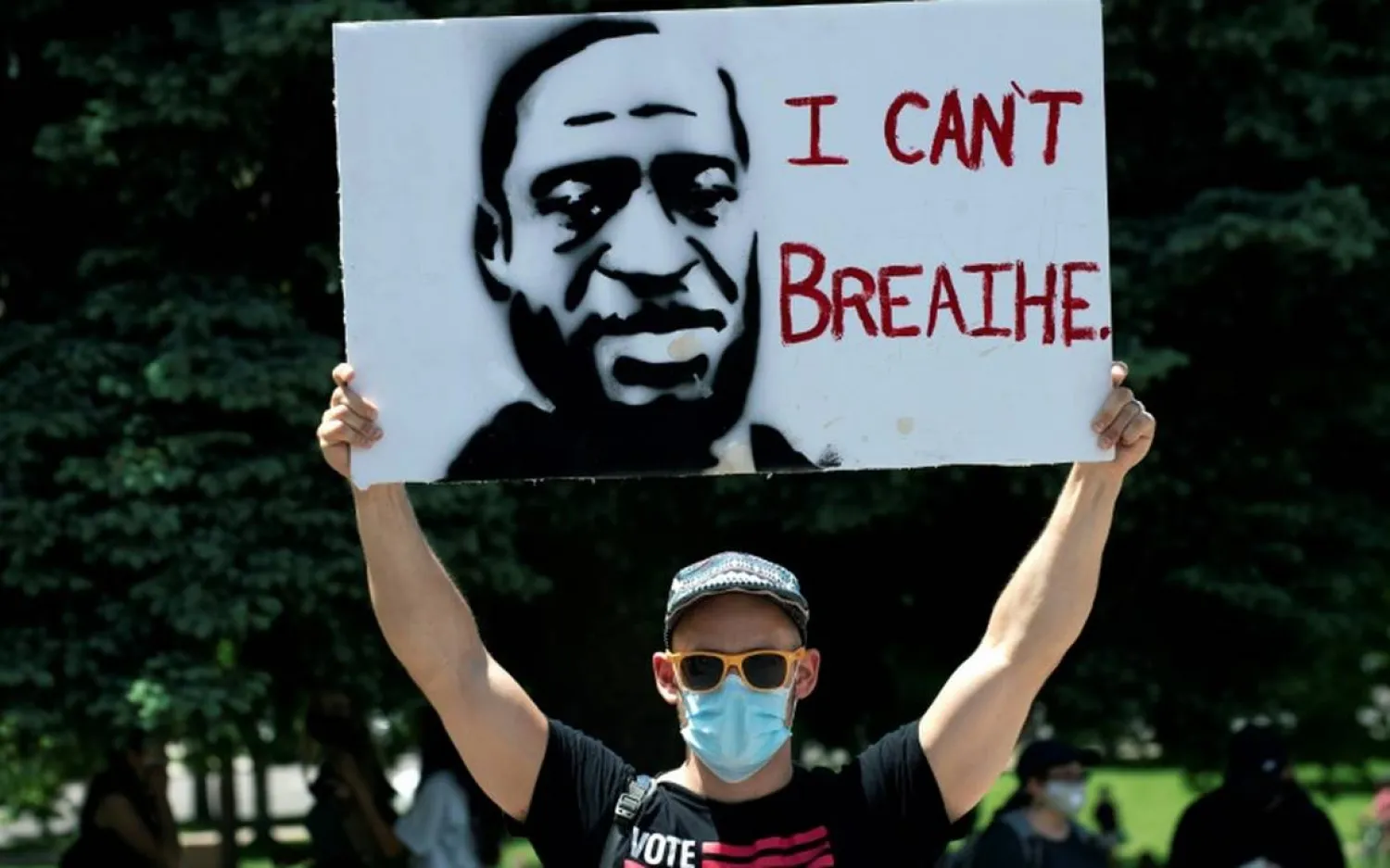 A demonstrator holds up a poster with a rendition of George Floyd on May 30 in Denver | AFP