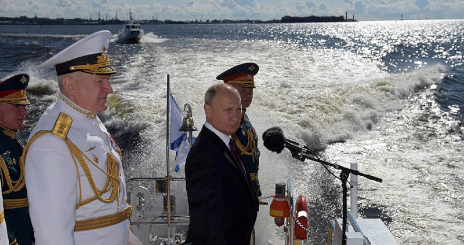 بوتين مع وزير الدفاع وقائد سلاح البحرية خلال العرض العسكري في سان بطرسبرغ أمس (أ.ف.ب)